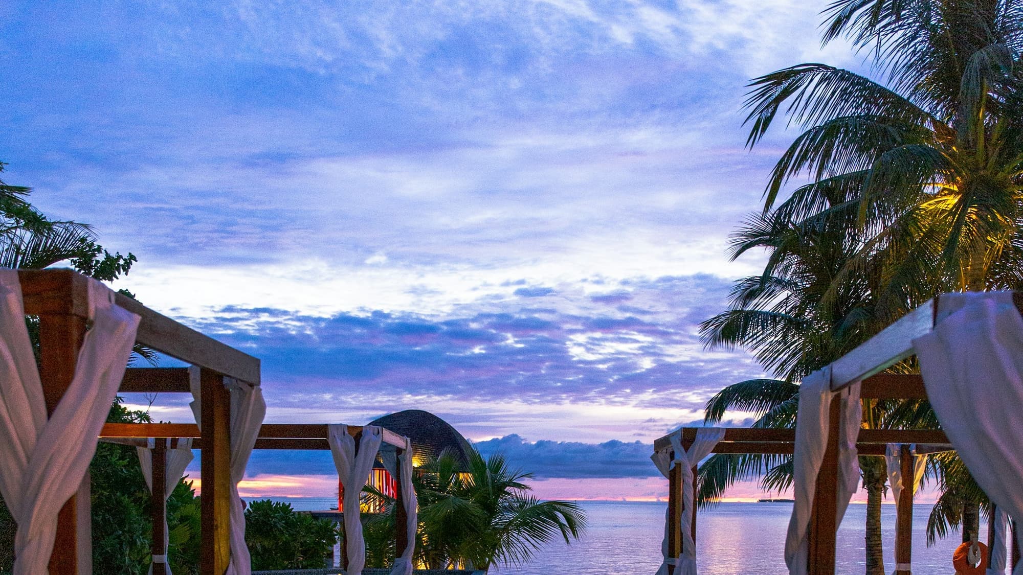 Negril coastline at golden hour from a villa terrace, sea and palms beyond, warm light