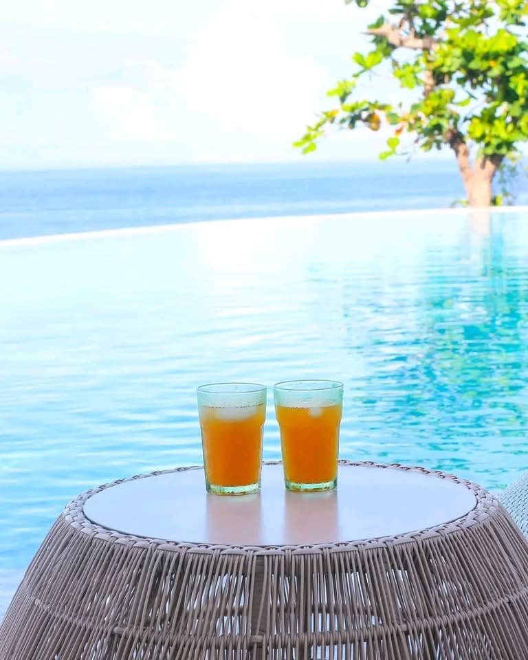 Two cold drinks on a table at the infinity pool edge, open sea beyond